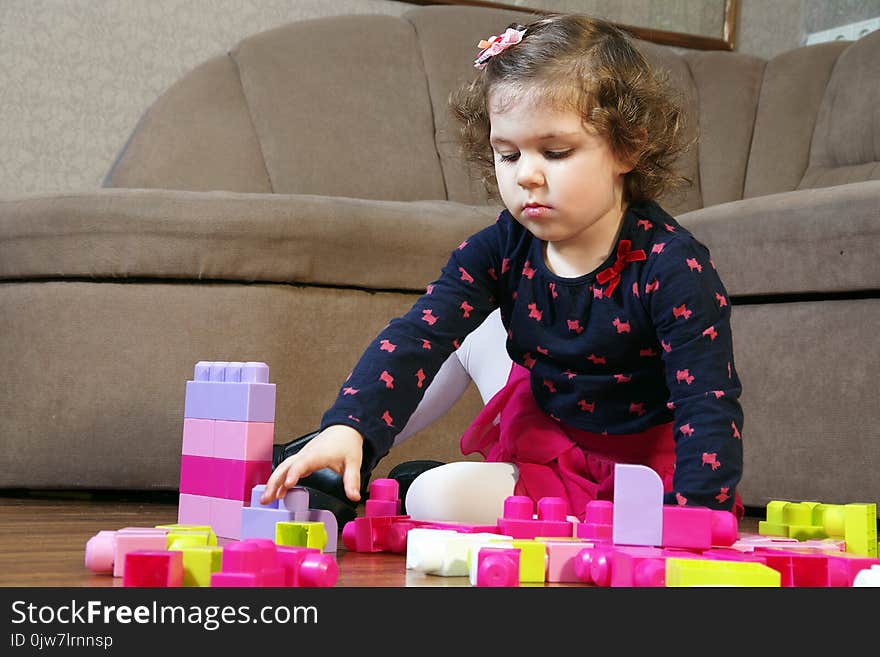 A little girl builds colorful plastic cubes. A little girl builds colorful plastic cubes