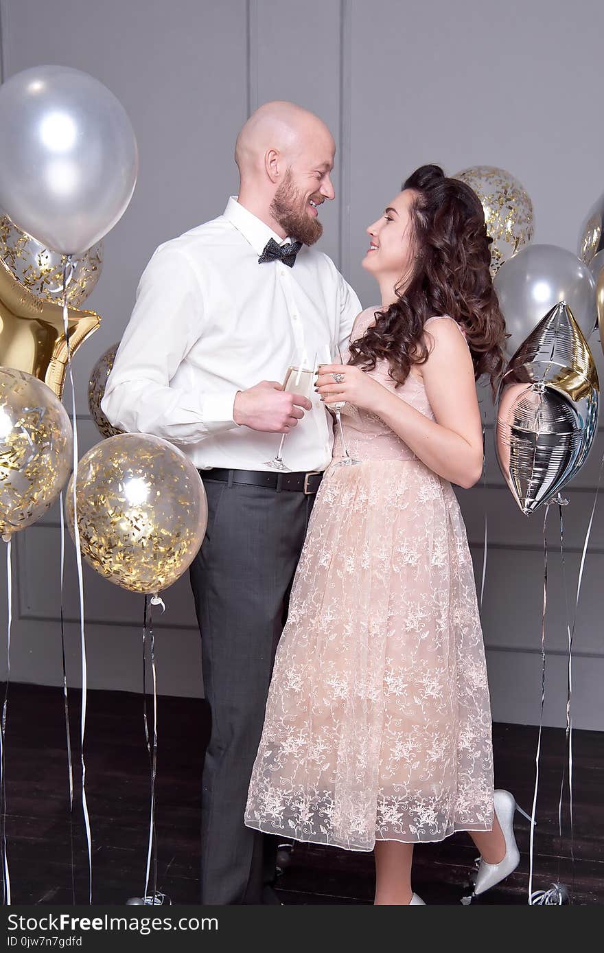 Handsome bald men with a beard hugs her girlfriend with glass of champagne. Handsome bald men with a beard hugs her girlfriend with glass of champagne.