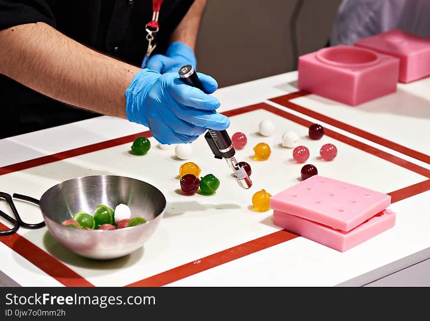 Confectioner with a burner prepares color sweet candy balls