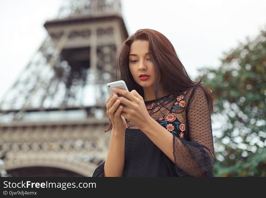 Travel woman using smartphone near the Eiffel tower and carousel, Paris.