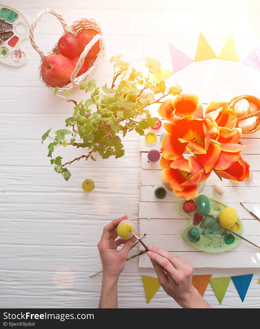 Man painting Easter eggs still life on a white wooden background