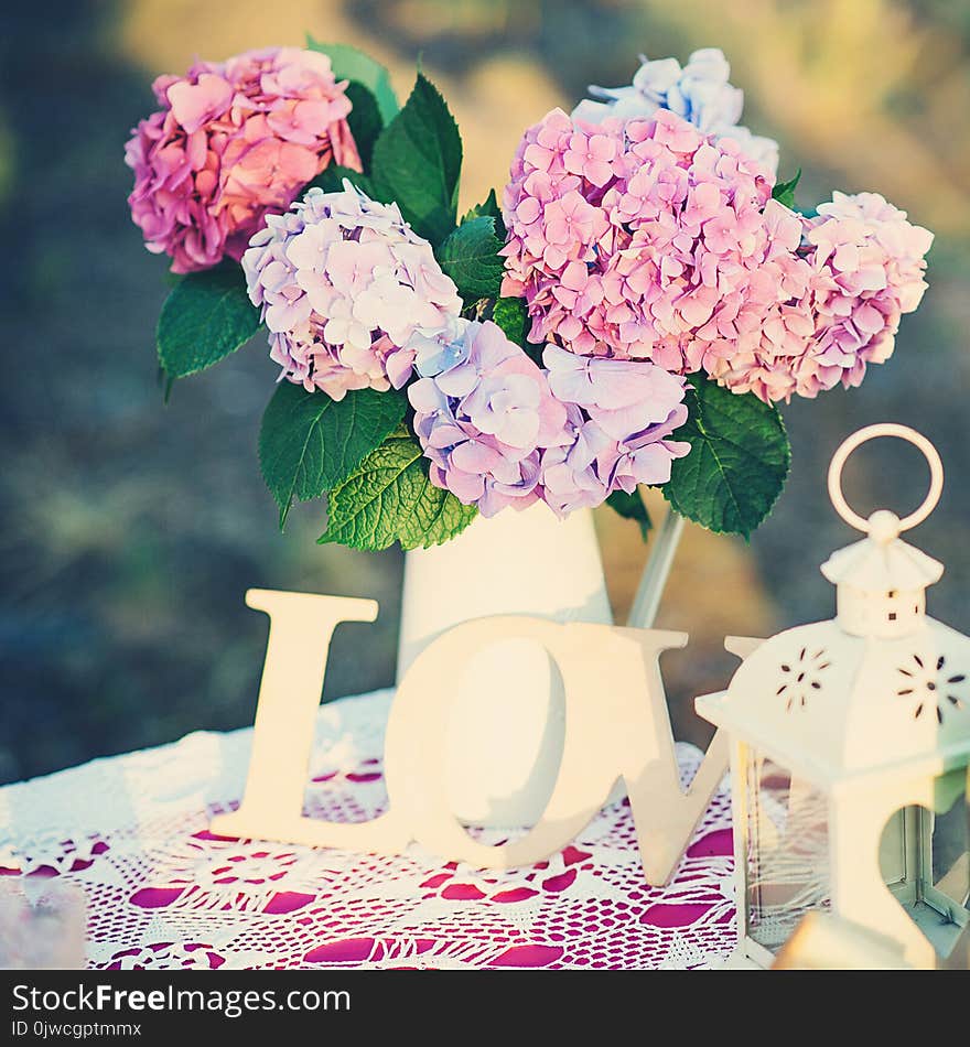 Pretty bouquet of hydrangea flowers in a vintage jar. Flower decor on the garden table.