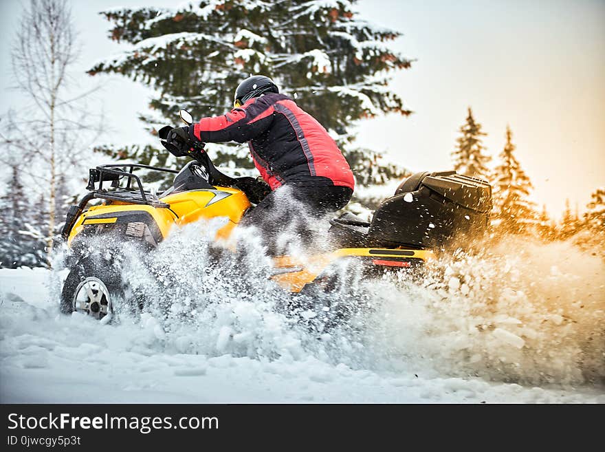 A man is riding an ATV in winter on the snow in his helmet. A man is riding an ATV in winter on the snow in his helmet.