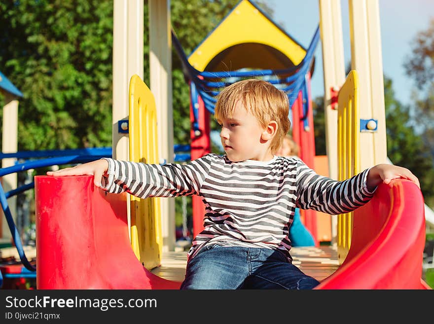 Happy little boy on the playground at sunny day.