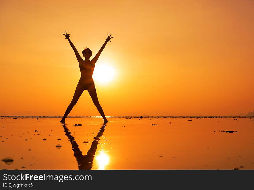 Silhouette of a young and fit woman on the beach at sunset