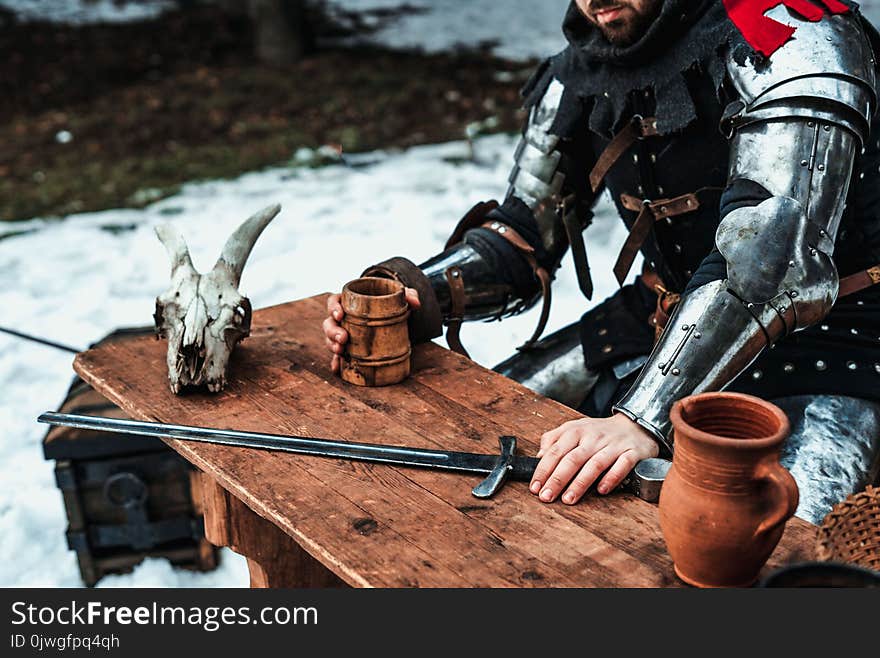 Male warrior sitting with a sword at a wooden table. Male warrior sitting with a sword at a wooden table