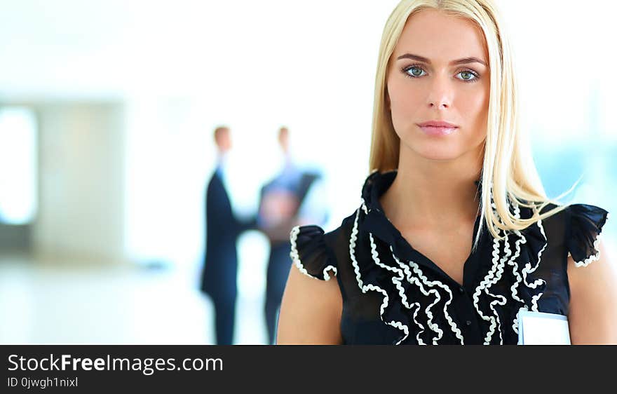 Business woman standing in foreground in office .