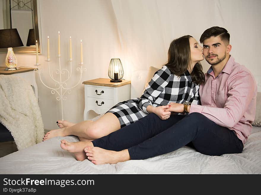 Young couple in love sitting on a bed at home. Young couple in love sitting on a bed at home