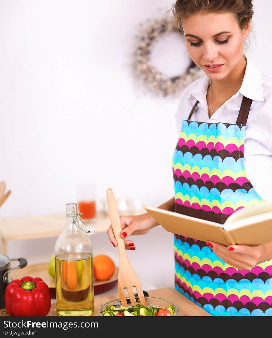 Young woman mixing fresh salad .