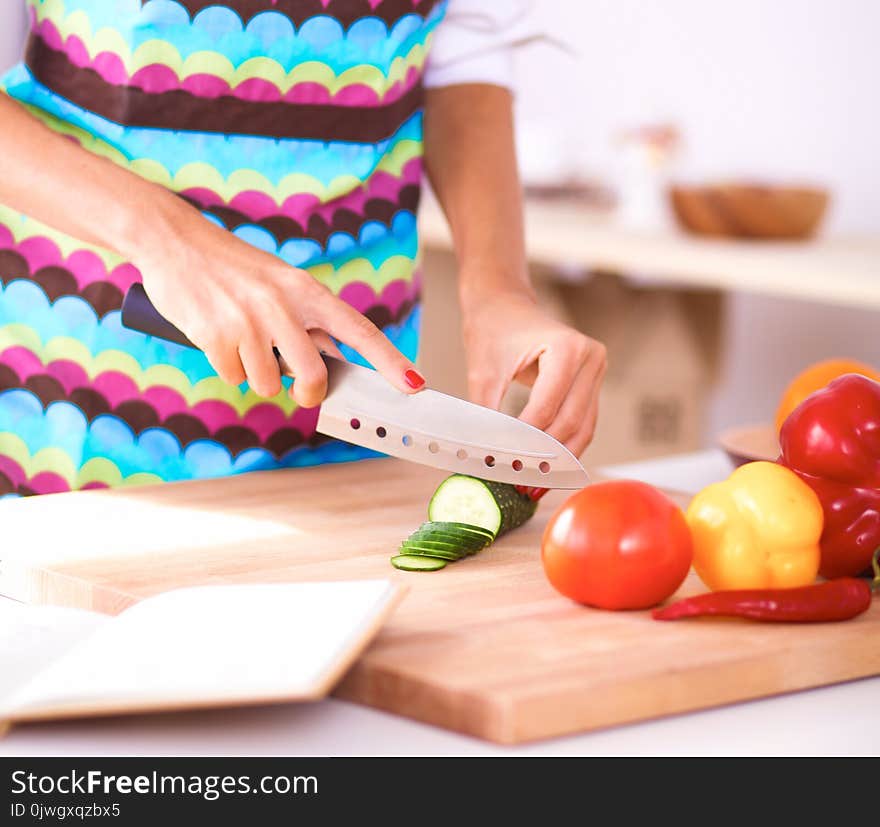 Young woman cutting vegetables in kitchen