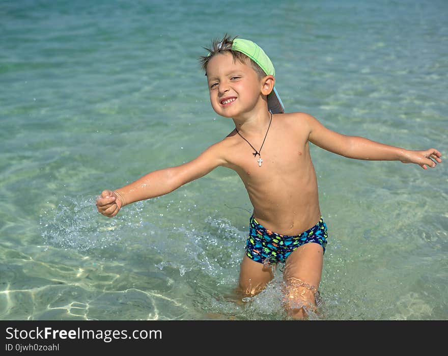 Happy smiling little boy run play with waves on beach. Italy. Summer