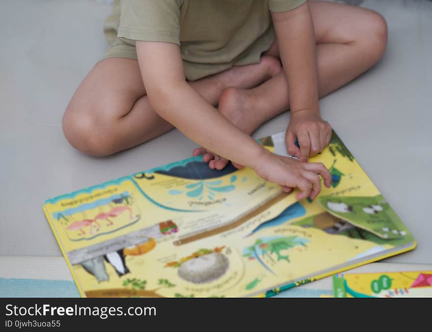 Boy sit on floor,reading colourful book in home school or learning concept