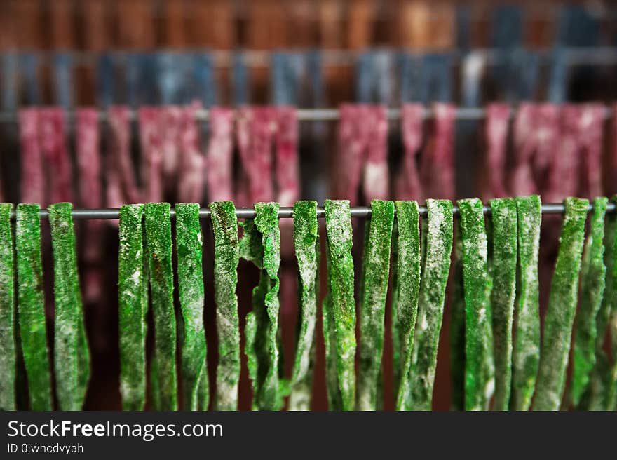 The homemade pasta paste is dried on the dryer. Green, red, blue, yellow fettuccine dries, textural background from pasta