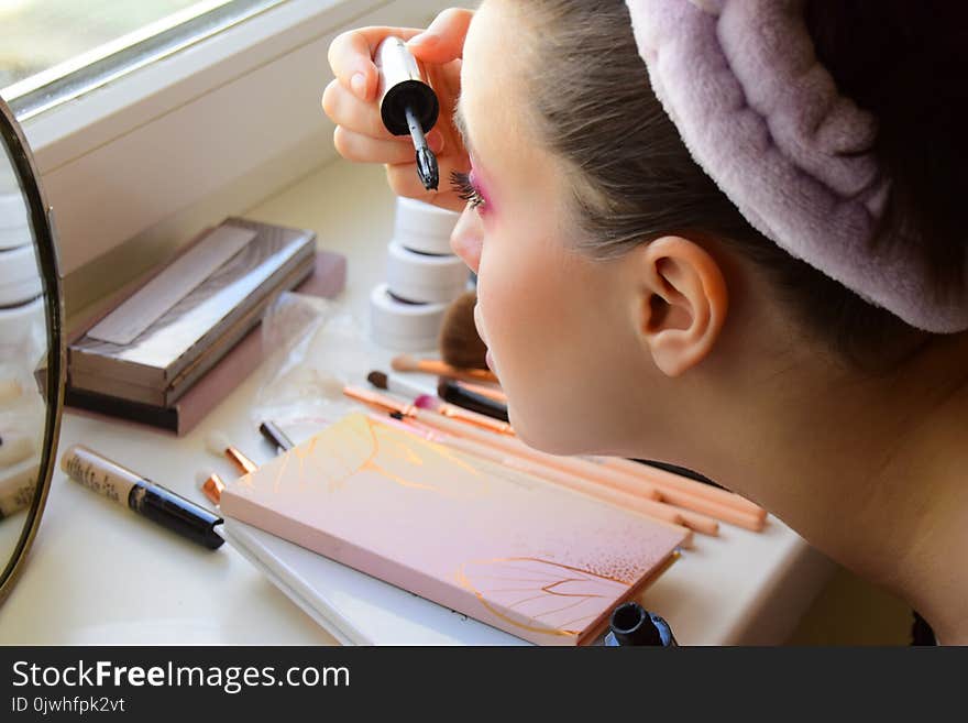 The young girl does a makeup of eyes and eyelashes.