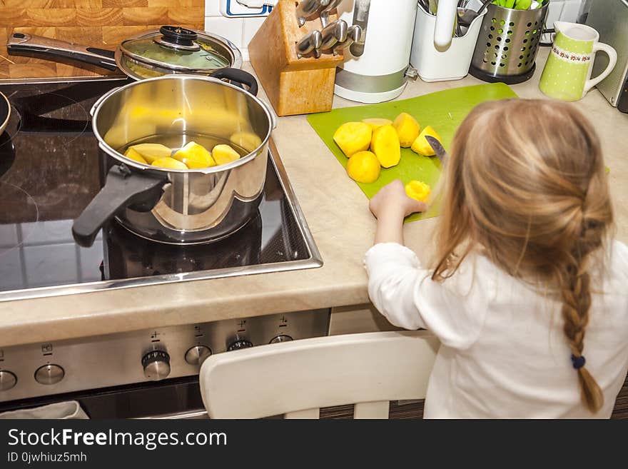 The little girl peeling and cutting potatoes