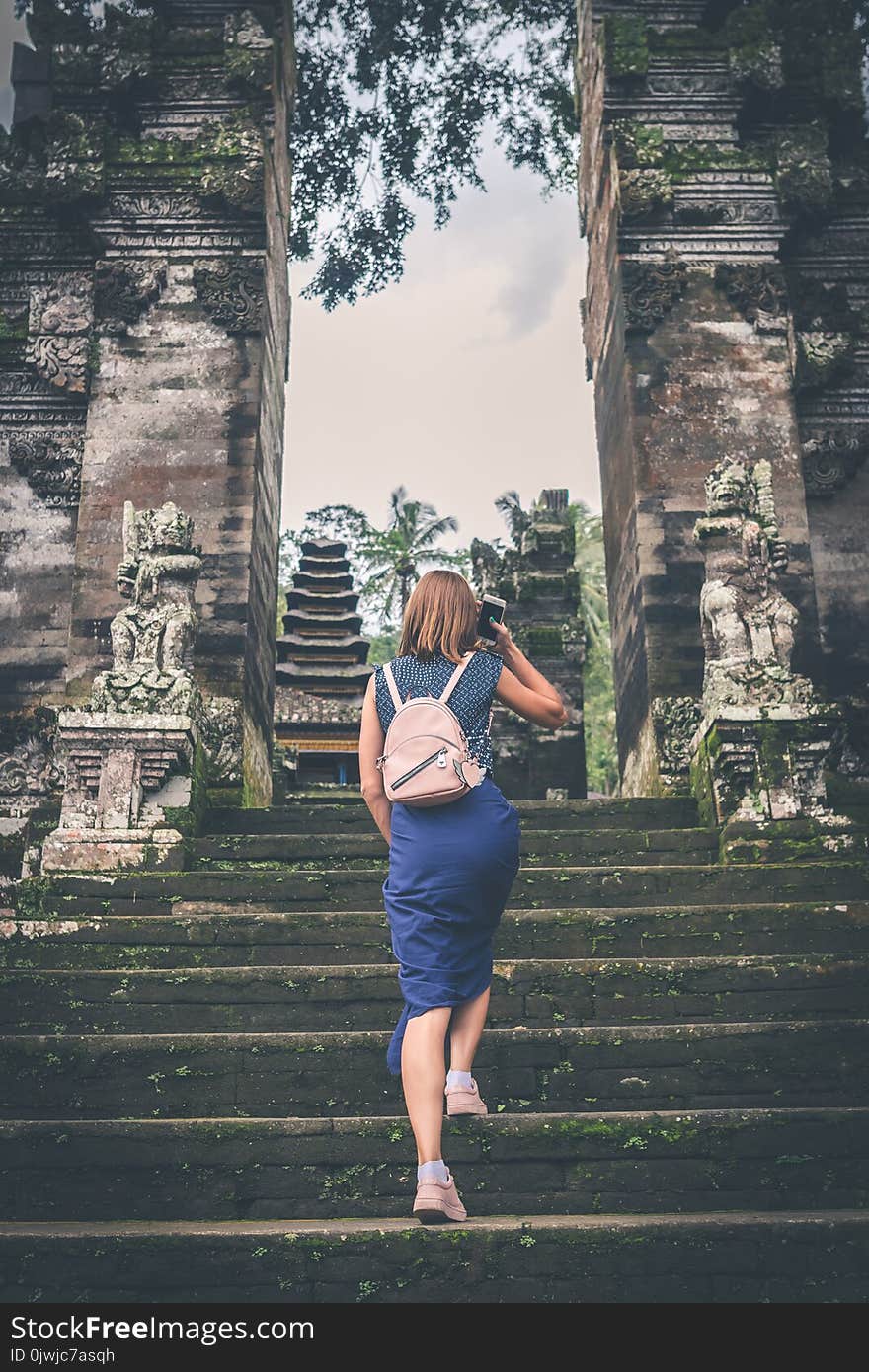 Woman in Blue Dress Walking on Concrete Staircase Leading to Buildings