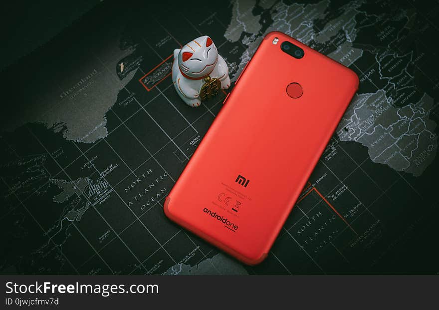 Red Xiaomi Mi Smartphone Beside White Cat Figurine