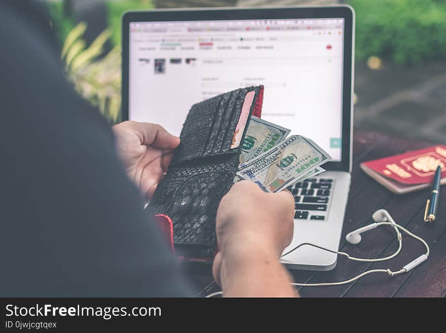 Person Holding 10 Us Dollar Banknote in Front of Gray and Black Laptop Computer