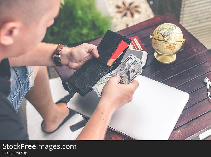 Man Holding U.s Dollar Banknotes and Black Leather Bi-fold Wallet