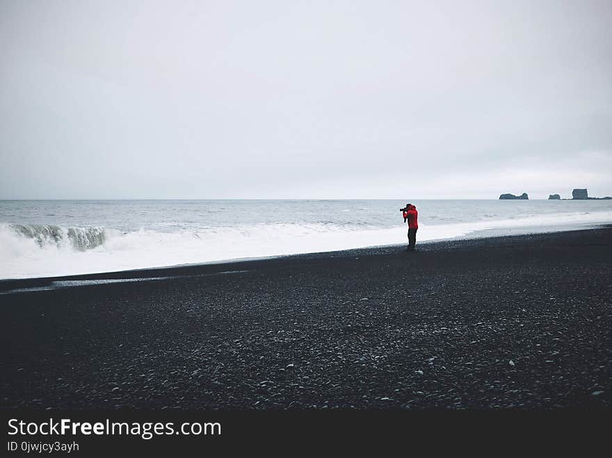 Person in Red Top Standing Near Body of Water