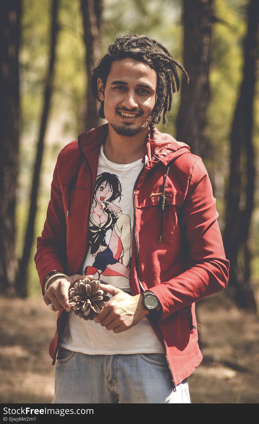 Man in Red Zip-up Hoodie Holding Pine Cone