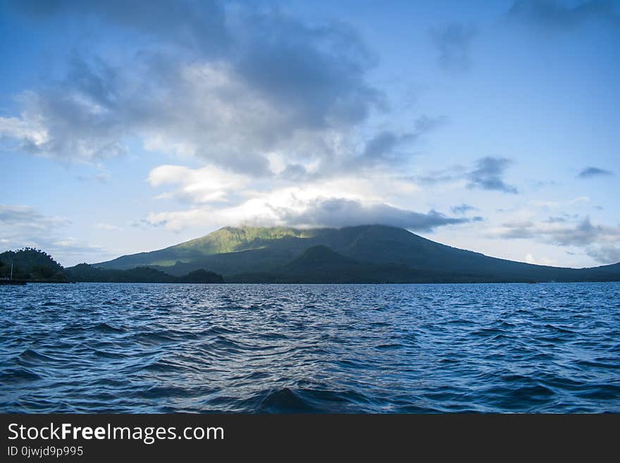 Ocean Near High Rise Mountain Cover With Fogs at Daytime