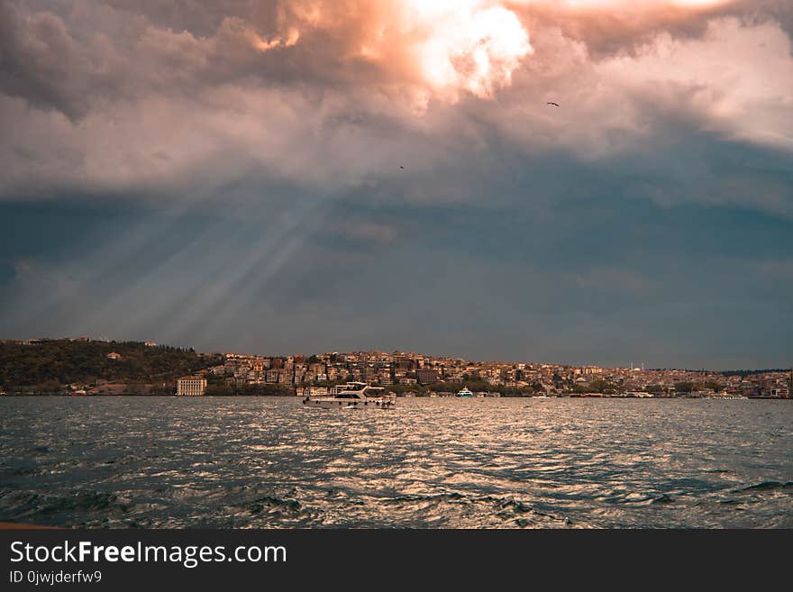 Concrete Buildings Near Sea Under White and Blue Cloudy Sky