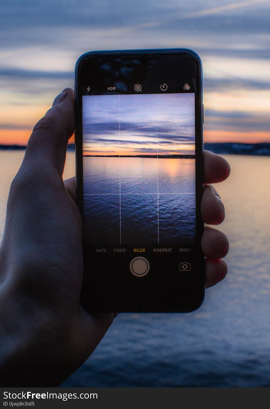 Person Holding Post-2014 Iphone Taking a Photo of Body of Water