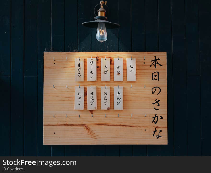 Kanji Printed Tags Hanged on Brown Wooden Board Lighted by Pendant Lamp