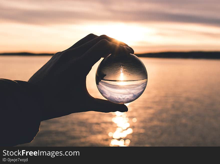 Photo Displays Person Holding Ball With Reflection of Horizon