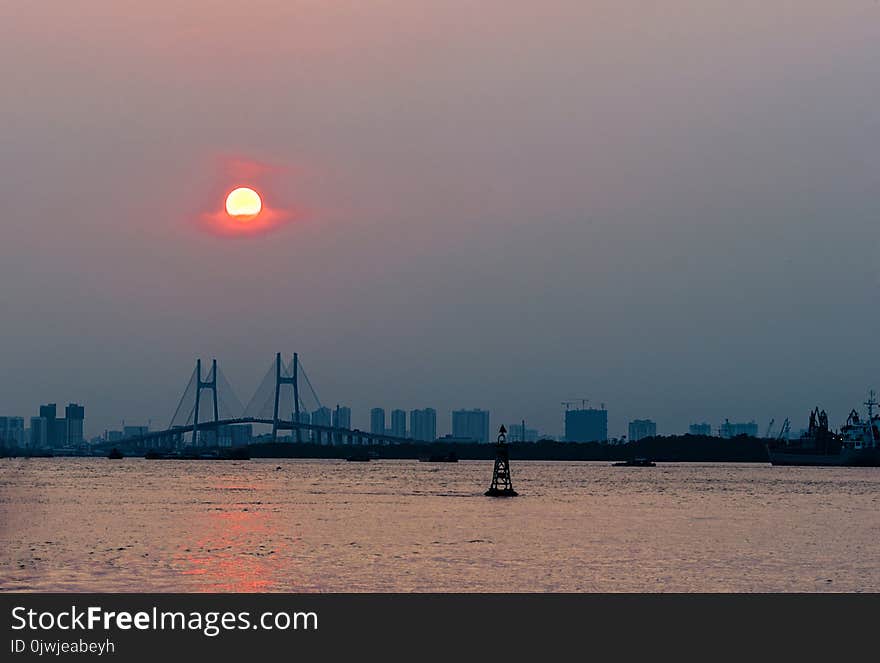 Ship Near Brown Bridge Across Sea during Sunset