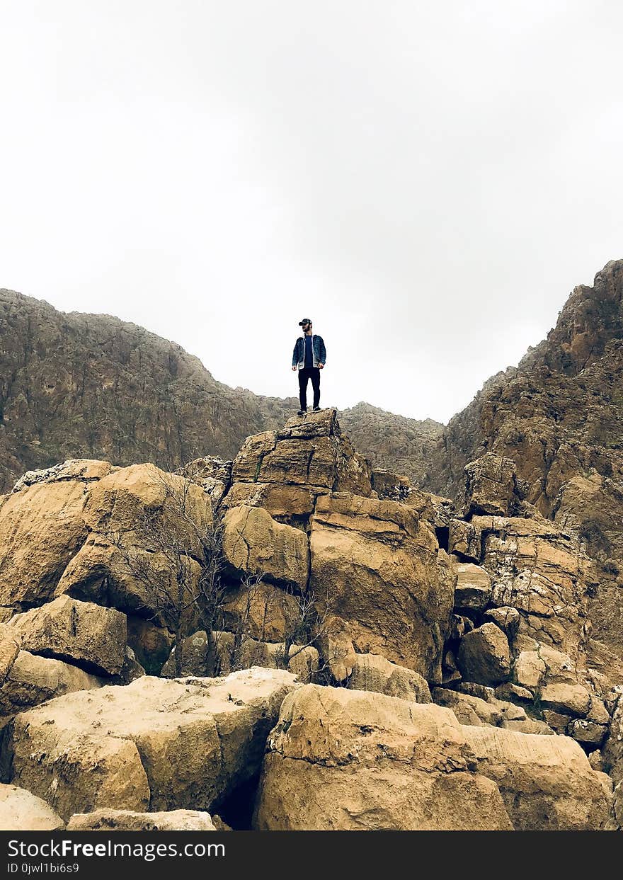 Man in Denim Jacket and Black Bottom Standing on Brown Concrete Stone