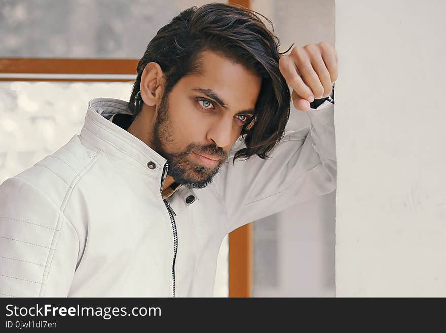 Man in White Zip-up Jacket Leaning on White Painted Wall