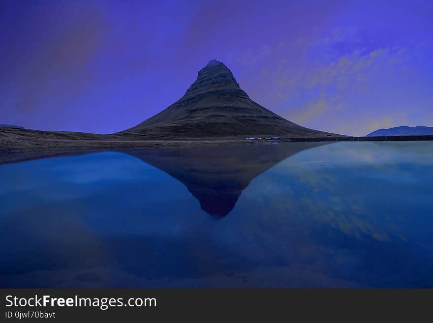 Kirjufell mountain with water reflection in the lake during sunset