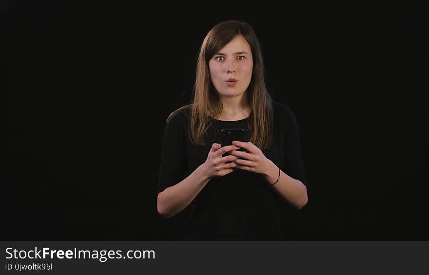 A Lady Using a Phone Against a Black Background