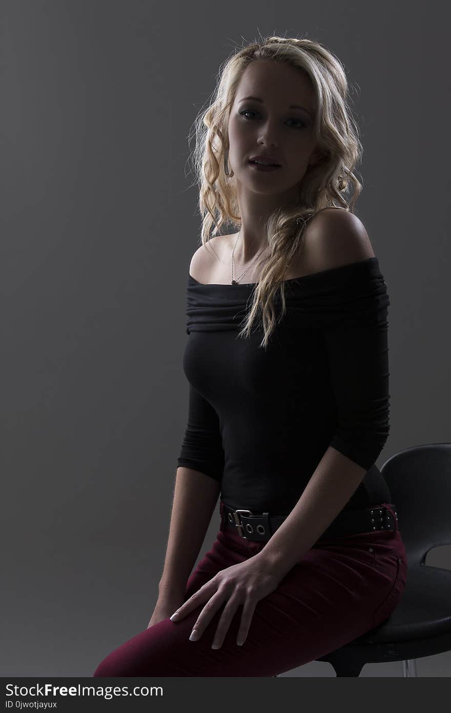 Beautiful blond woman in curly hair and black top and red pants