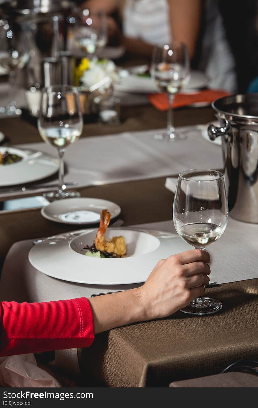 Woman holds glass of white wine. people consider the color of the wine and try how it smells in different glasses