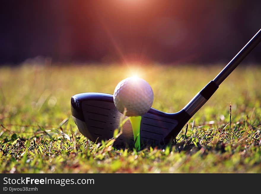 Blurred golf club and golf ball close up in grass field with sunset. Golf ball close up in golf coures at Thailand