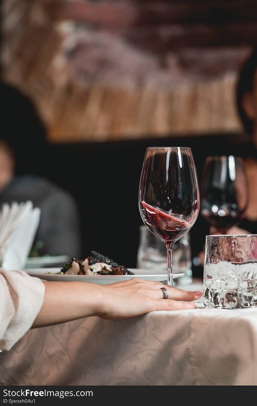 Woman holds glass of red wine. people consider the color of the wine and try how it smells in different glasses