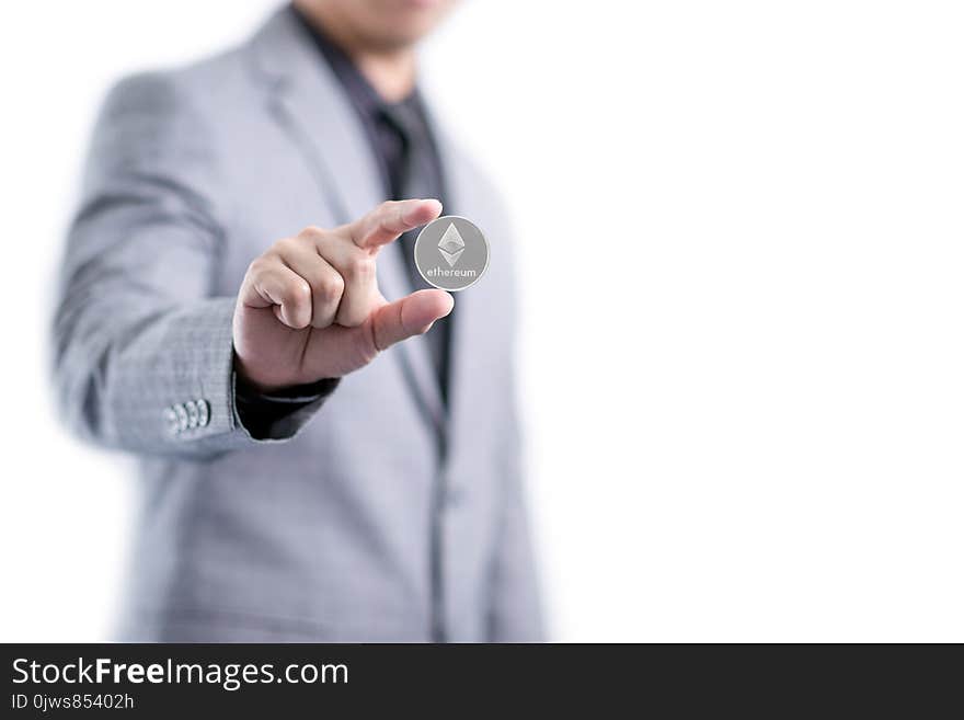 Businessman In Gray Suit Is Holding Silver Ethereum Coin Between Fingers