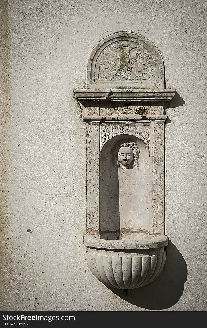 Small historical water fountain on the old yellowed wall in the ancient Moravian town