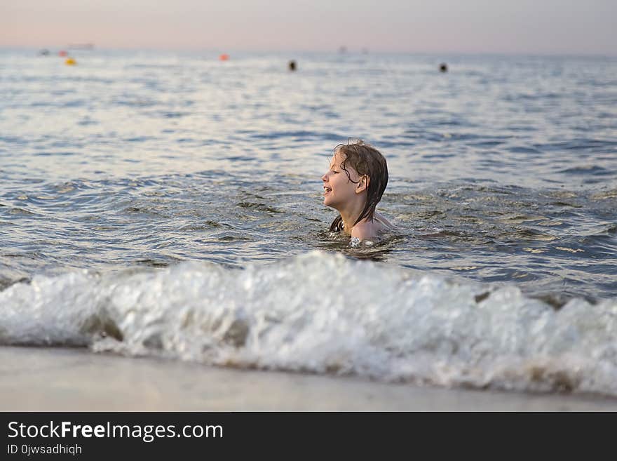 Seven-year-old girl bathes the sea waves in the rays of the sunset. Seven-year-old girl bathes the sea waves in the rays of the sunset