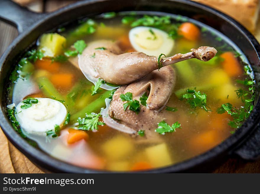 Soup with quail meat, with quail eggs and vegetables, in a frying pan