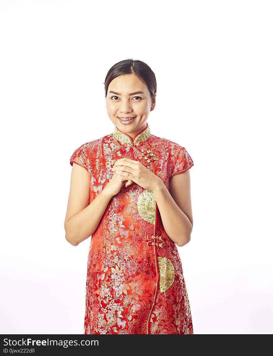 Happy Chinese New Year Portrait of Asian Chinese girl blessing, in traditional red qipao standing on plain background.