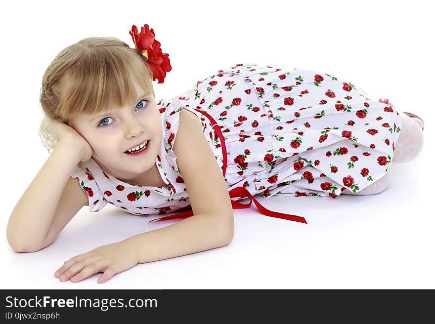 Beautiful little girl lies on the floor on a white background. The concept of a happy childhood, well-being in the family. .