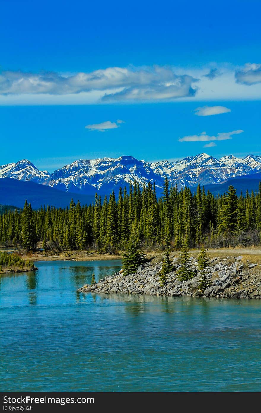 The north Saskatchewan river meanders along the rocky shoreline with mountains in the background. The north Saskatchewan river meanders along the rocky shoreline with mountains in the background