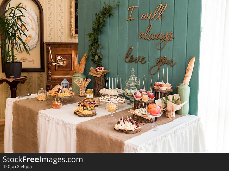 A rustic table, sealed with cheese, nuts, fruits and sweets. A wooden background.