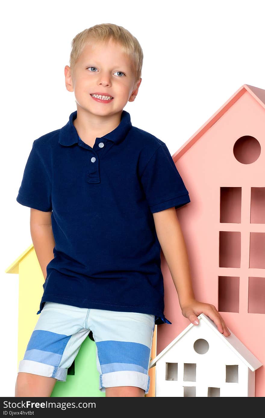 A little boy is playing with colorful houses. The concept of family happiness, the development of the child in kindergarten or in the family. Isolated on white background.