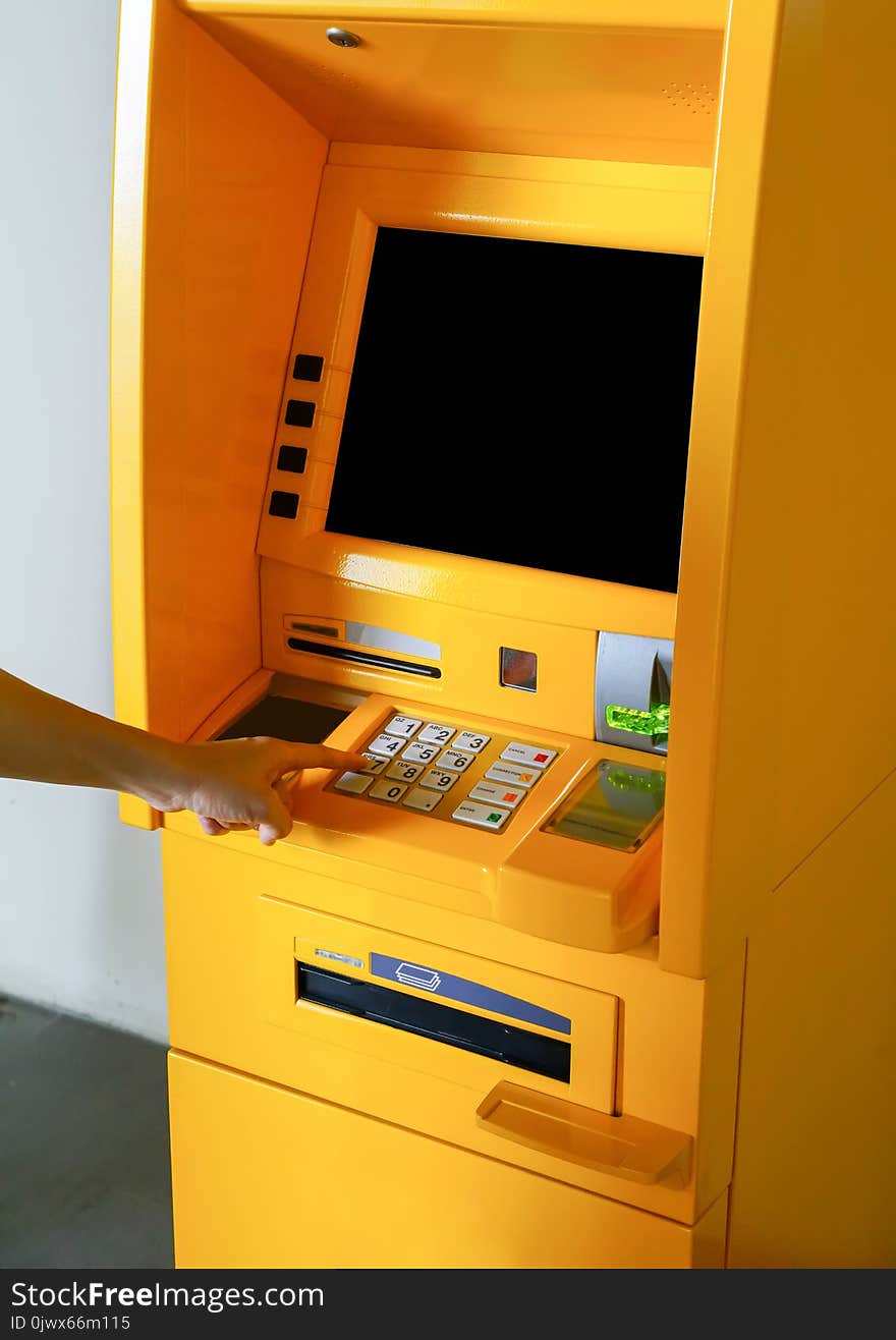 Asian woman looking at monitor screen while pressing digit buttons on ATM machine.