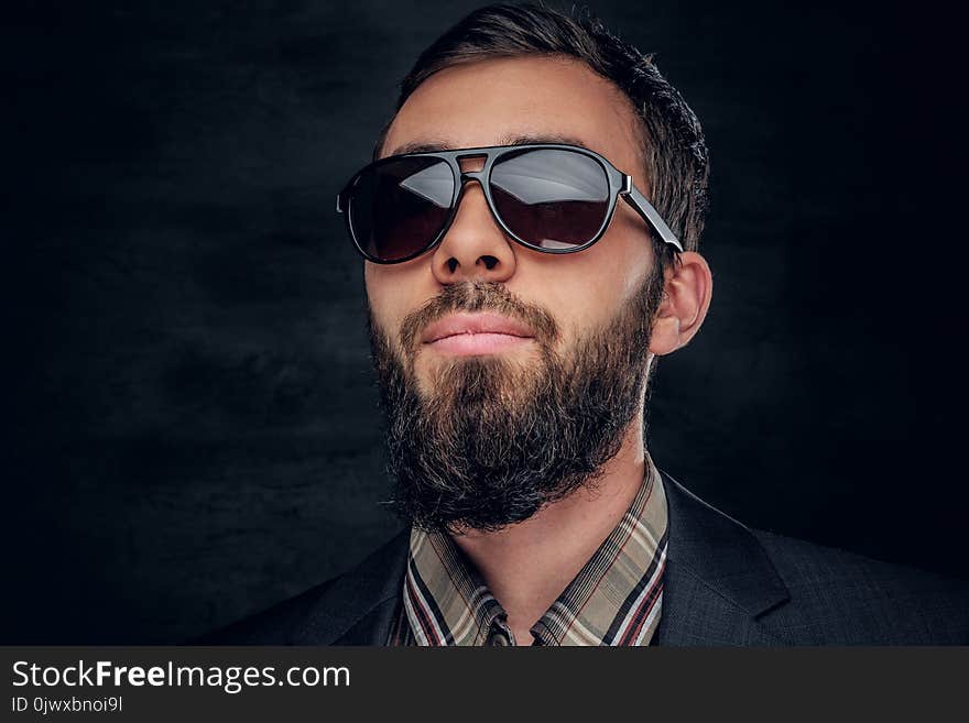 Close up portrait of bearded male in sunglasses on grey vignette background. Close up portrait of bearded male in sunglasses on grey vignette background.